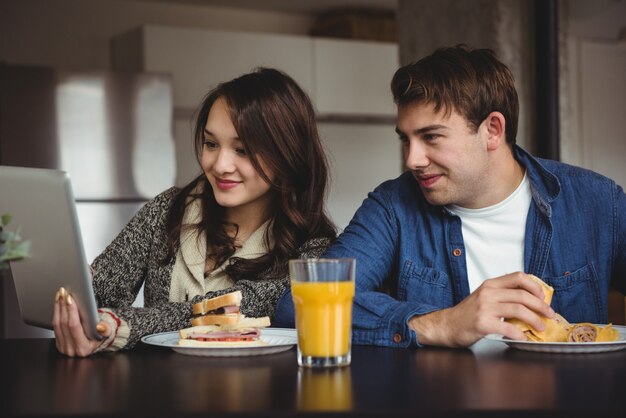 Pareja usando tableta digital mientras desayuna