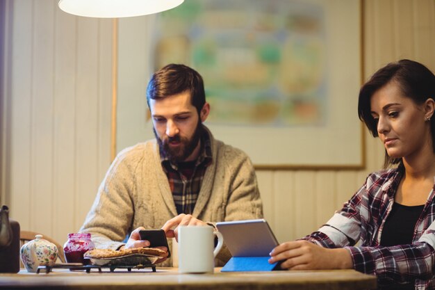 Pareja usando tableta digital y teléfono móvil