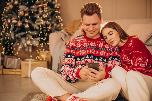 Pareja usando el teléfono juntos en Navidad