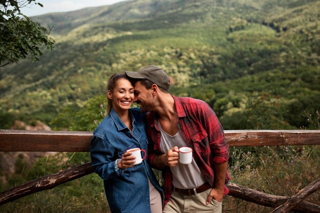 Pareja viajando en la naturaleza y disfrutando de una bebida.