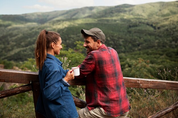 Pareja viajando en la naturaleza y disfrutando de una bebida.