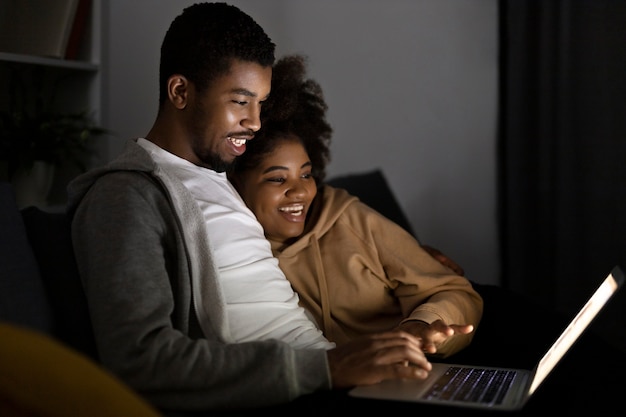 Pareja viendo servicio de streaming en casa en interiores