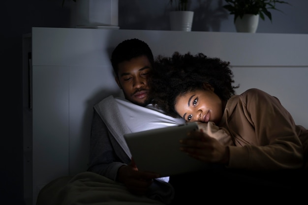 Pareja viendo servicio de streaming en casa en interiores