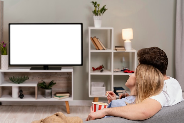 Pareja viendo la televisión y comiendo palomitas de maíz