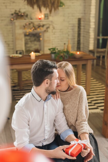 Pareja vinculante con caja de regalo en casa.