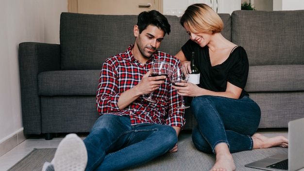 Pareja con vino en la computadora portátil