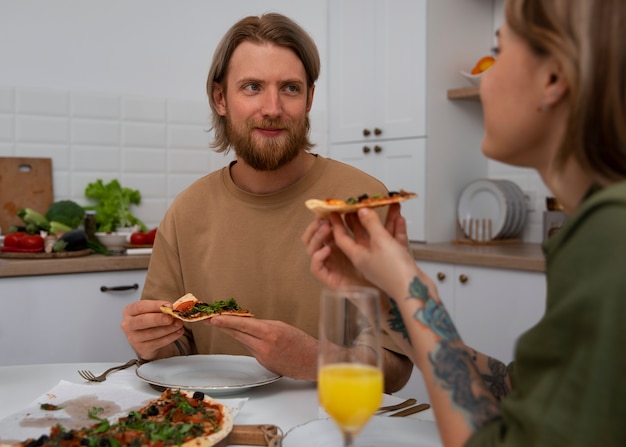 Foto gratuita pareja de vista lateral con deliciosa pizza