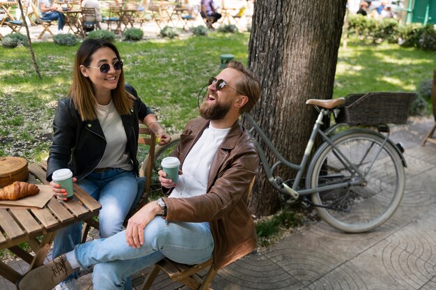 Pareja vistiendo chaquetas de cuero sintético tomando café juntos al aire libre