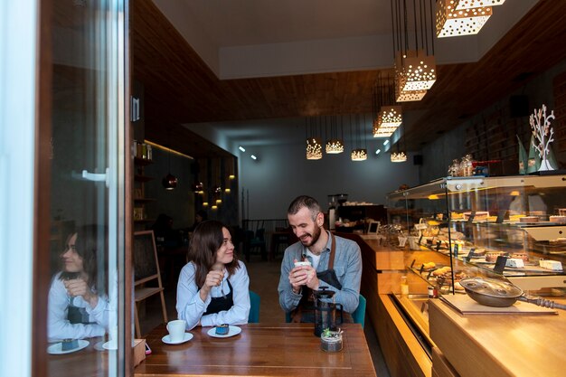 Pareja vistiendo delantales en cafetería