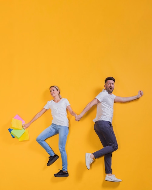 Foto gratuita pareja volando con bolsas