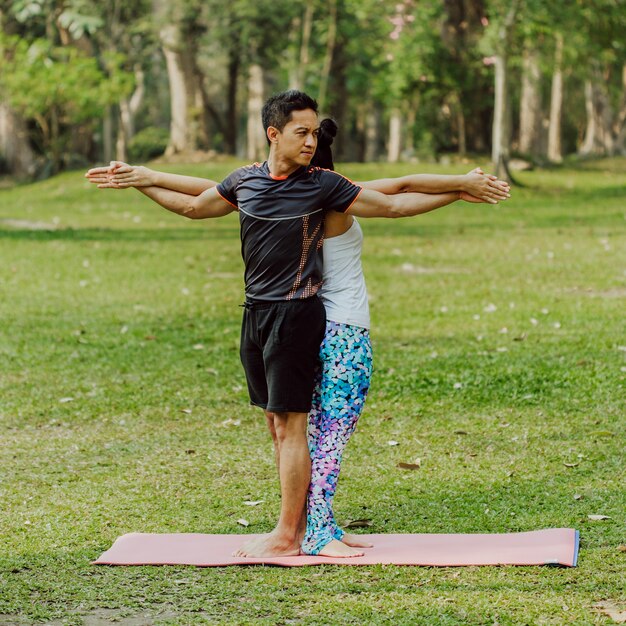 Pareja, yoga, hierba y árboles