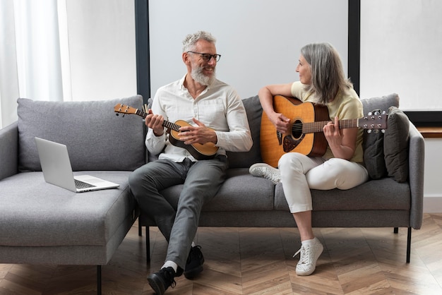 Las parejas ancianas en casa estudiando lecciones de guitarra y ukelele en portátil