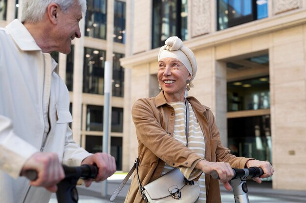 Las parejas ancianas montando un scooter eléctrico en la ciudad