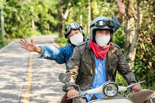 Las parejas ancianas montando un scooter en nuevos viajes normales