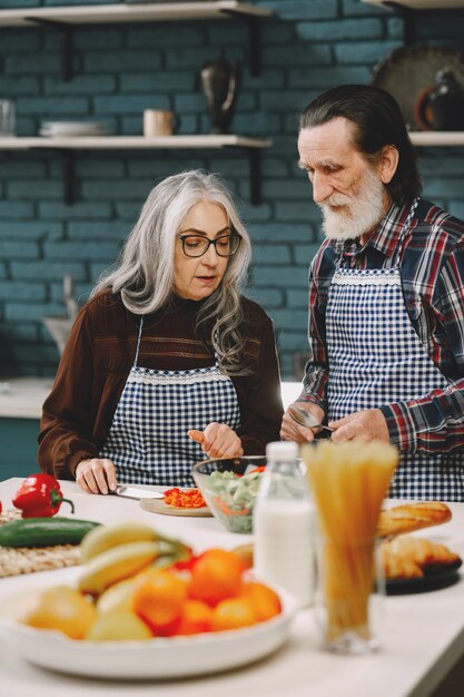 Las parejas ancianas preparando la comida en la cocina