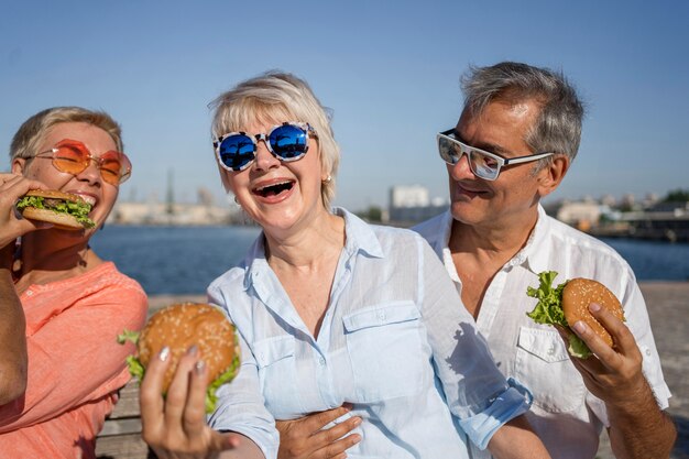 Parejas de ancianos en la playa disfrutando de hamburguesas