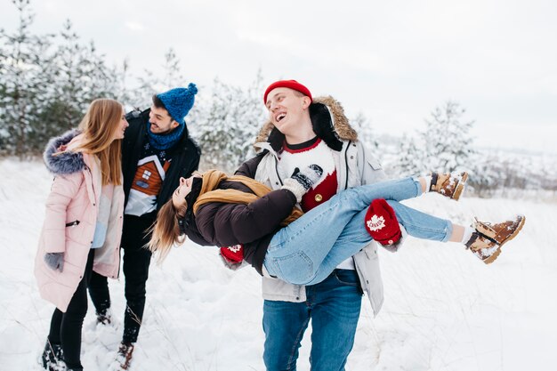 Parejas felices divirtiéndose en el bosque de invierno