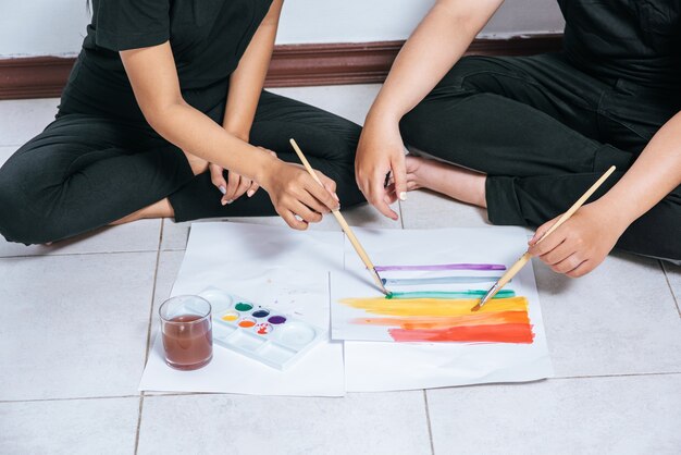 Las parejas femeninas dibujan y pintan sobre papel.