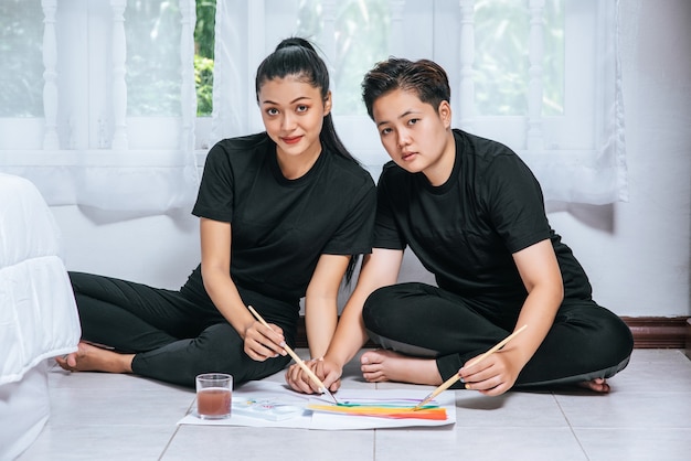 Las parejas femeninas dibujan y pintan sobre papel.