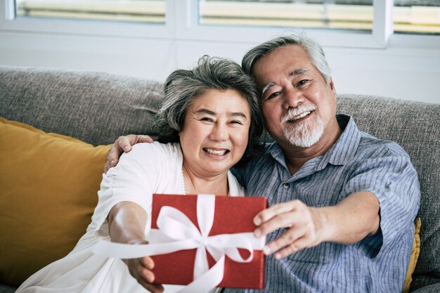 Parejas mayores Sorpresa y caja de regalo en el salón.