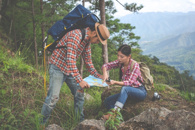 Las parejas ven un mapa en un bosque tropical con mochilas en el bosque. Aventura, senderismo, escalada.