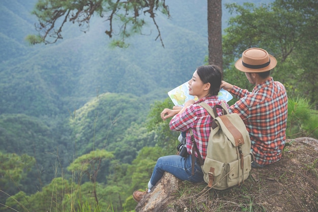 Las parejas ven un mapa en un bosque tropical con mochilas en el bosque. Aventura, senderismo, escalada.