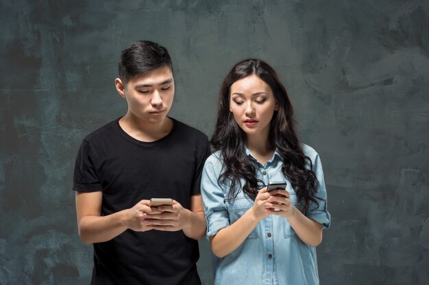 Pares jovenes asiáticos usando el teléfono celular, retrato del primer.