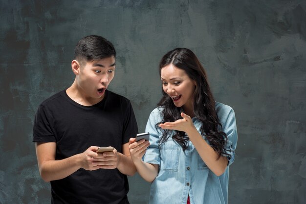 Pares jovenes asiáticos usando el teléfono celular, retrato del primer.