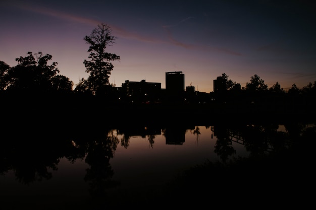 Un parque en la ciudad con el reflejo del lago del edificio al amanecer.