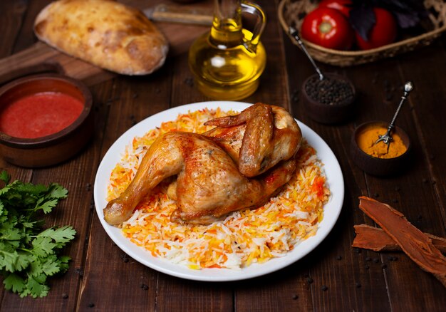 Parrilla de pollo entero servido con guarnición de arroz en plato blanco.