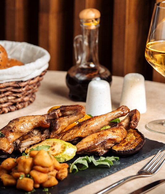 Parrilla de pollo frito con papas fritas sobre tabla de madera