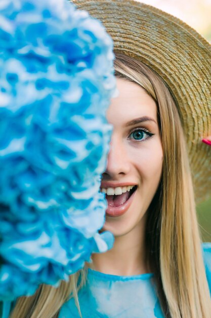 Parte de la cara. Retrato de mujer joven bonita con sombrero de paja con media cara cerca de la flor de hydragea.