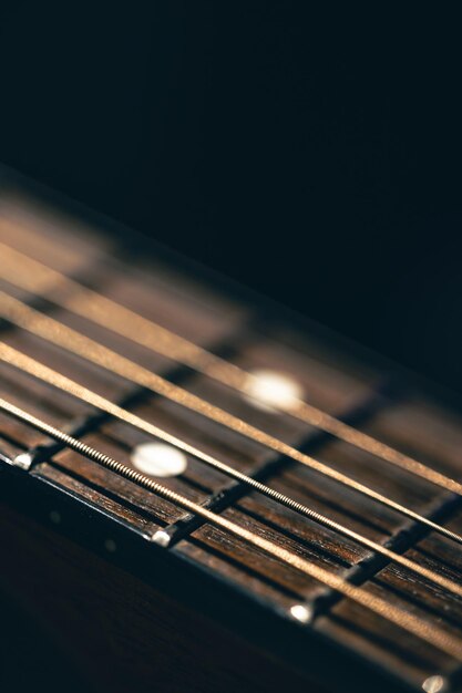 Foto gratuita parte de un fretboard de guitarra acústica en un fondo negro