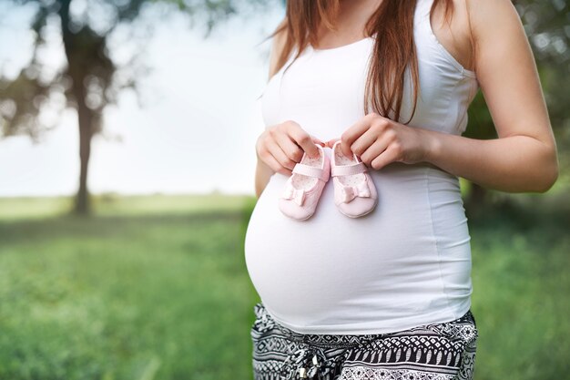 Parte de la mujer embarazada con zapatitos para bebé