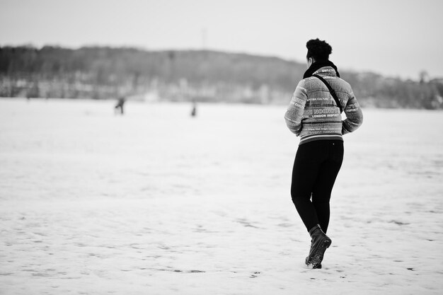 La parte posterior de la mujer africana se viste con una pose de bufanda negra en el día de invierno en Europa