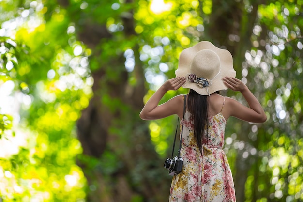 La parte posterior de la niña de la felicidad con un sombrero de paja en el jardín