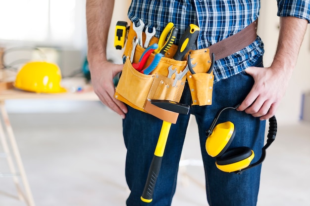 Parte del trabajador de la construcción con cinturón de herramientas