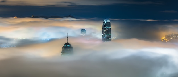 Partes superiores de rascacielos cubiertos de niebla por la noche