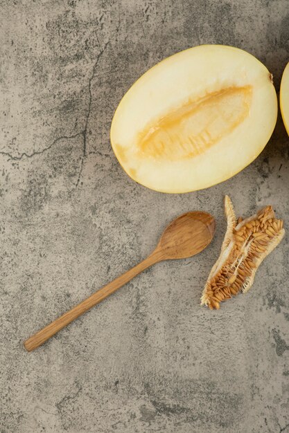 Partió a la mitad deliciosos melones amarillos en la superficie de mármol con una cuchara de madera a un lado.