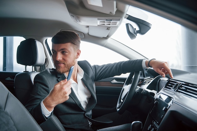 Pasajero en asiento trasero. Hombre de negocios moderno probando su nuevo coche en el salón del automóvil