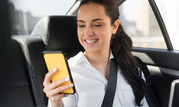 Foto gratuita pasajero usando su teléfono móvil en el auto