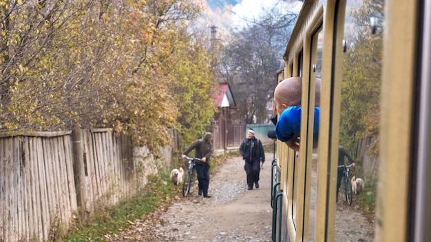 Pasajeros se asomaron por las ventanas del tren a vapor Mocanita moviéndose a través de un pueblo