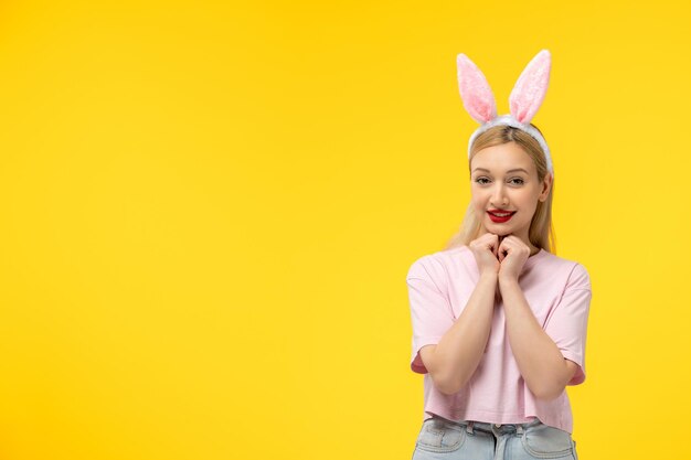 Pascua adorable bastante joven chica rubia con orejas de conejo felizmente tomados de la mano bajo la barbilla