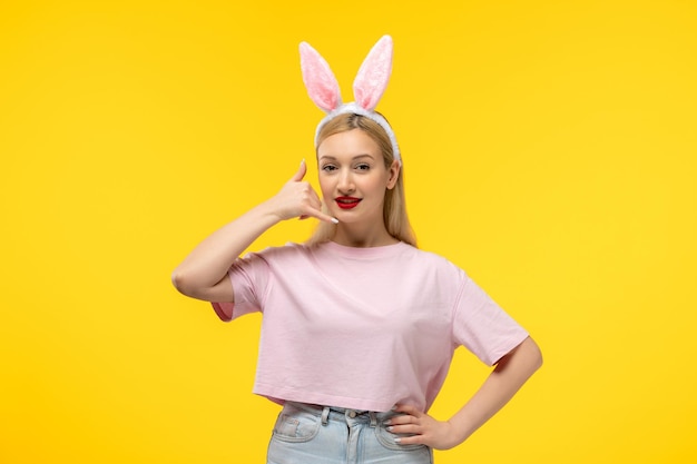 Pascua adorable bastante joven rubia con orejas de conejo haciendo gesto de llamada telefónica