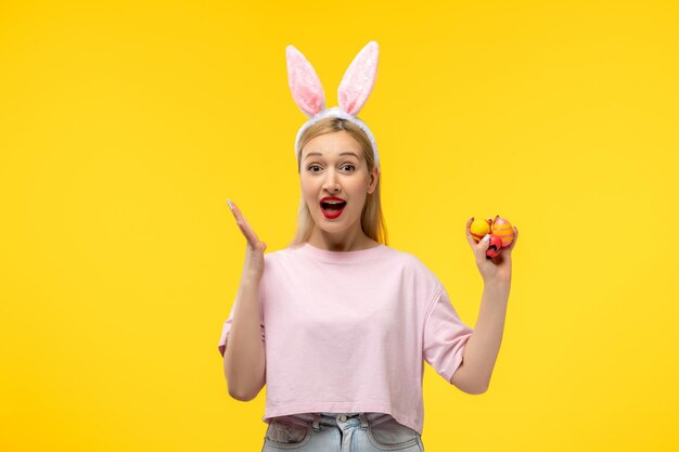 Pascua hermosa linda chica rubia con orejas de conejo emocionada sosteniendo huevos de pascua