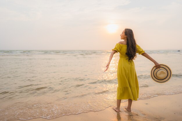 El paseo asiático joven hermoso de la mujer del retrato en la playa y el océano del mar con sonrisa feliz se relajan