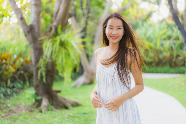 El paseo asiático joven hermoso de la mujer del retrato con la sonrisa feliz y se relaja en el parque