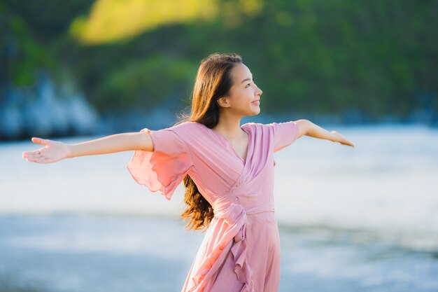 Paseo feliz de la sonrisa asiática joven hermosa de la mujer del retrato en el mar al aire libre tropical de la playa de la naturaleza