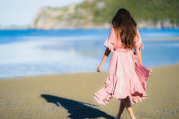 Paseo feliz de la sonrisa asiática joven hermosa de la mujer del retrato en el mar al aire libre tropical de la playa de la naturaleza