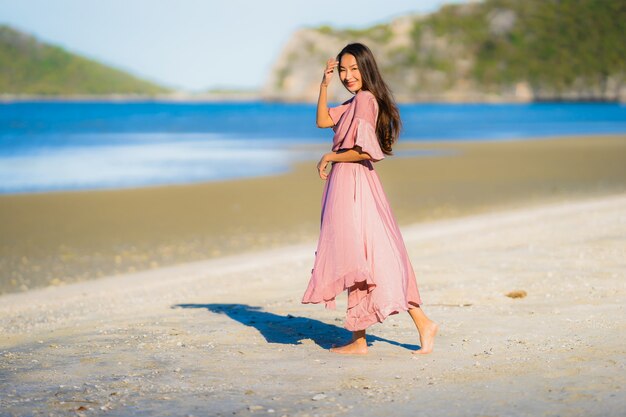 Paseo feliz de la sonrisa asiática joven hermosa de la mujer del retrato en el mar al aire libre tropical de la playa de la naturaleza